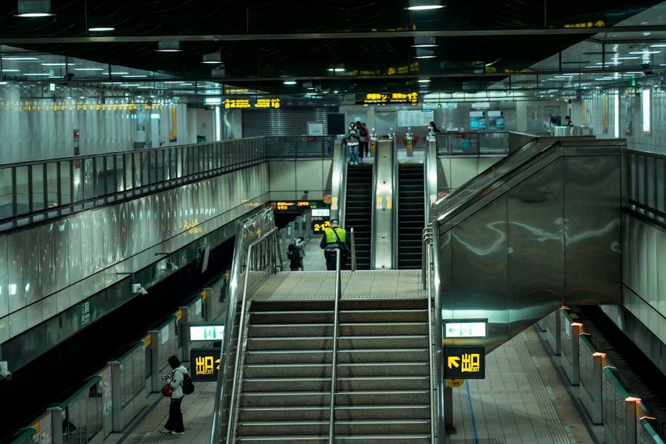 A worker at Selhurst station, dressed in dark clothing and a high-visibility vest, stands beside a large trolley loaded with black, orange, and gray garbage bags filled with waste. The trolley is posi